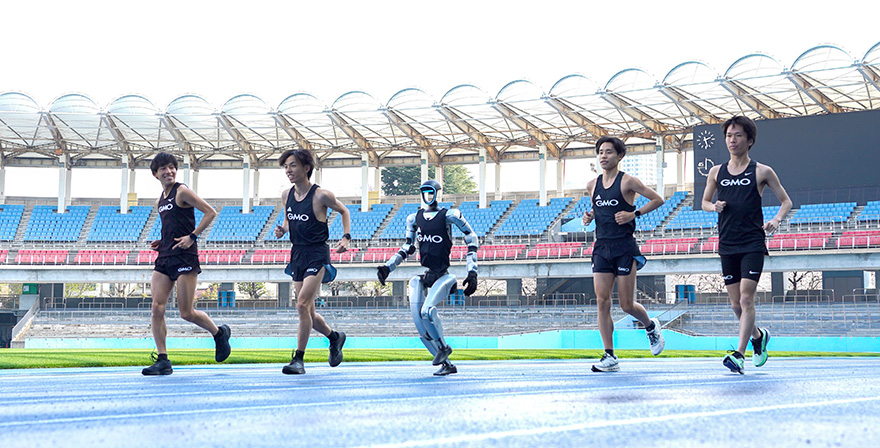 会見に参加したヒューマノイドと走るGMOインターネットグループ陸上部の選手たち（左から嶋津雄大選手、黒田朝日選手、今江勇人選手、吉田祐也選手）