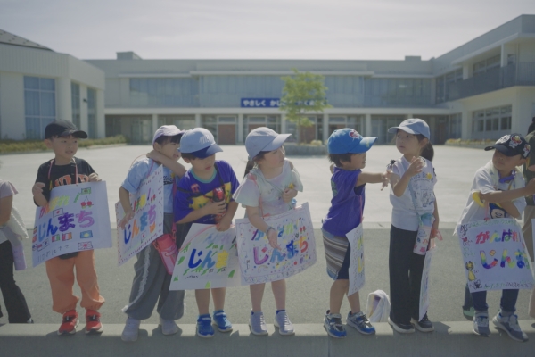 地域の小学生がプラカードを持って声援を送った