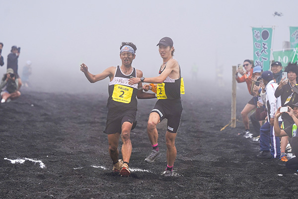 7区から8区へタスキを渡す平成山岳会の上田瑠偉選手（写真左）と吉野大和選手